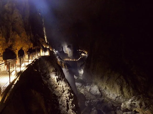 Tourists walking along a lighted path inside a vast cave