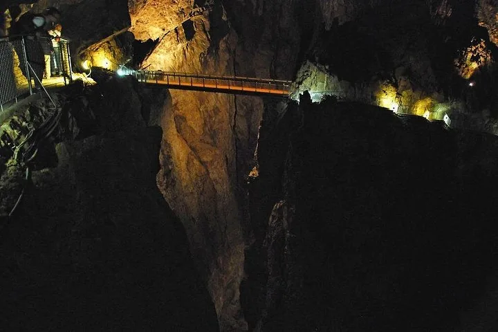 Illuminated bridge over a deep gorge inside a dark cave