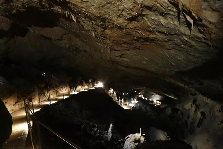 Visitors walking through a large, illuminated underground cave system