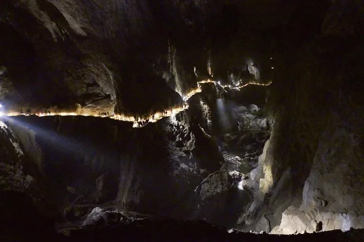 Illuminated walking path winding through a massive dark cave