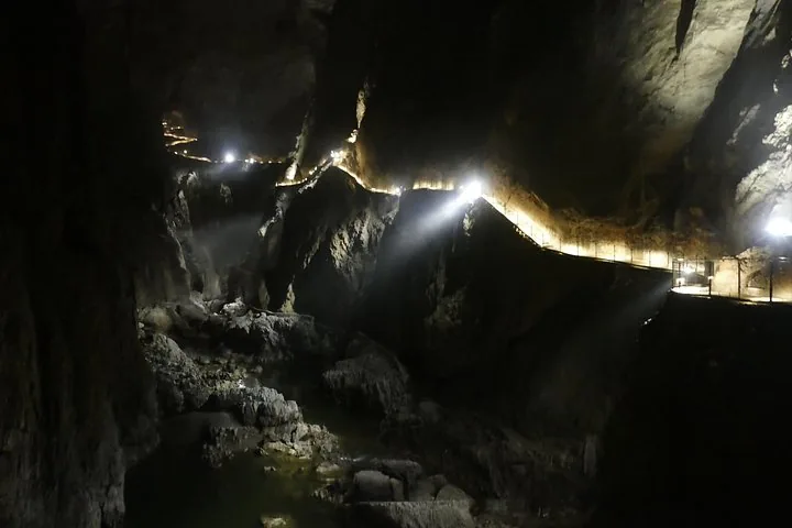 Brightly lit walkway and stairs inside a large, deep cave