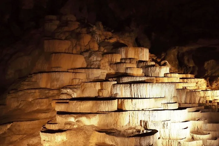 Terraced rock formations illuminated inside a dark underground cave
