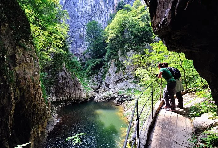 Hikers on a trail looking at an underground river gorge