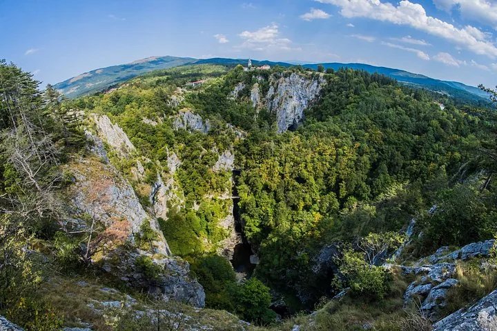 View of a gorge with lush green forest and distant hills
