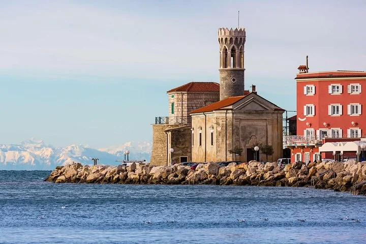 Lighthouse and historic buildings on a rocky breakwater near Piran